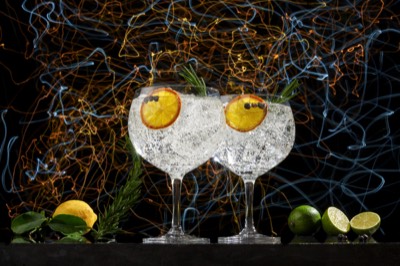  Two glasses of gin and tonic with lemon and lime and light trails background 