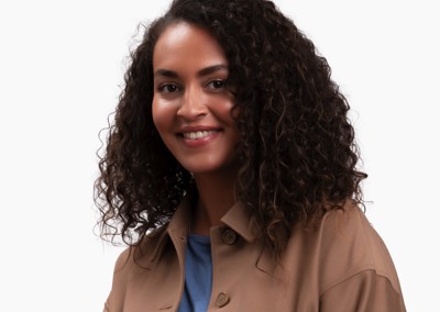  Headshot of smiling girl with curly hair and brown jacket  